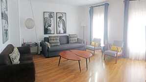 A modern living room with a grey sofa, two armchairs, a coffee table, and artwork on the walls. - Design, quality, tranquility, and very central (Alicante)