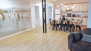 A modern living room with a wooden floor, a dining area with a wooden table and chairs, a kitchen with white cabinets and appliances, and a large wall mural of horses. - Design, quality, tranquility, and very central (Alicante)