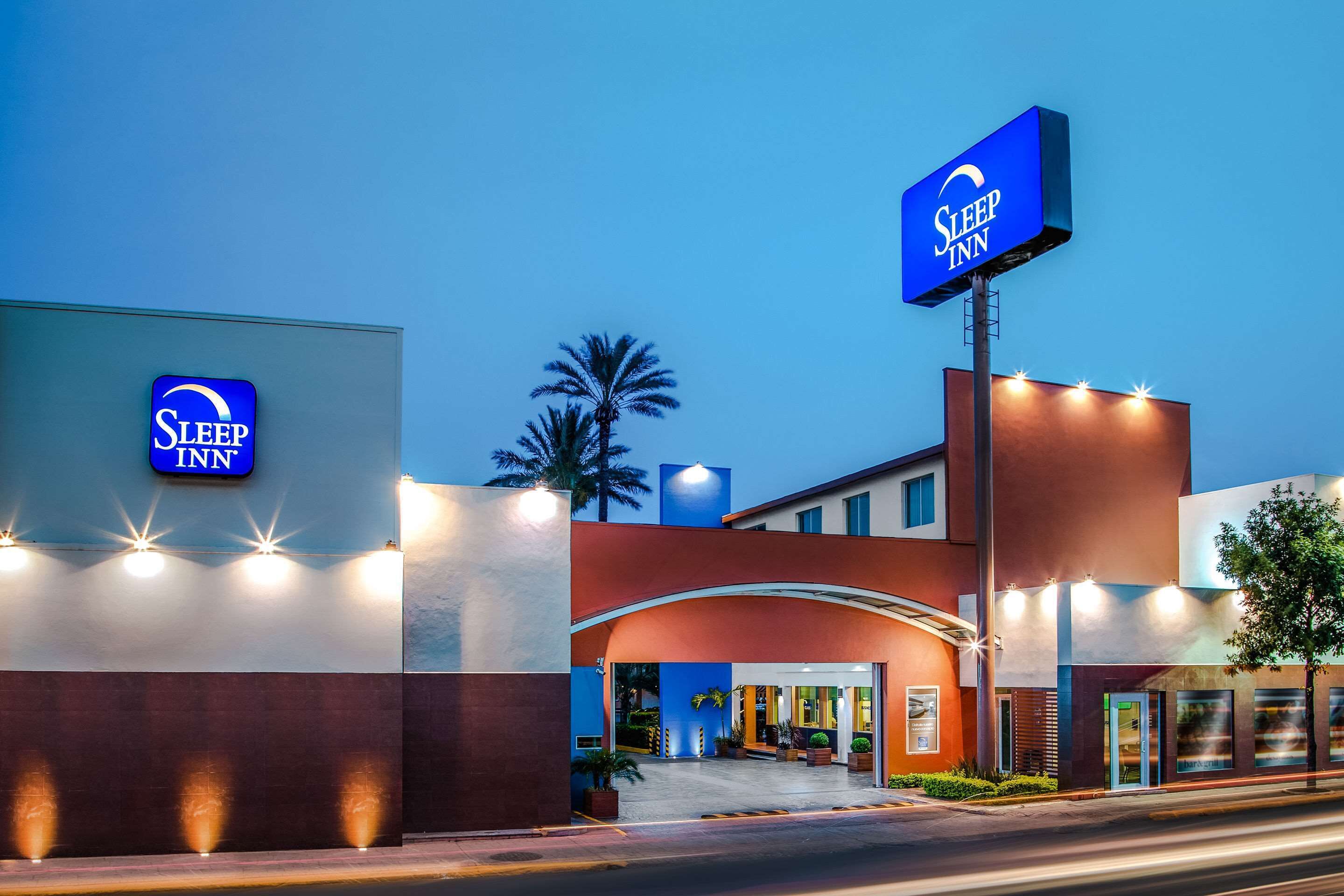 L’entrée d’un hôtel Sleep Inn, avec une enseigne bien visible, une arche incurvée et une façade bien éclairée.