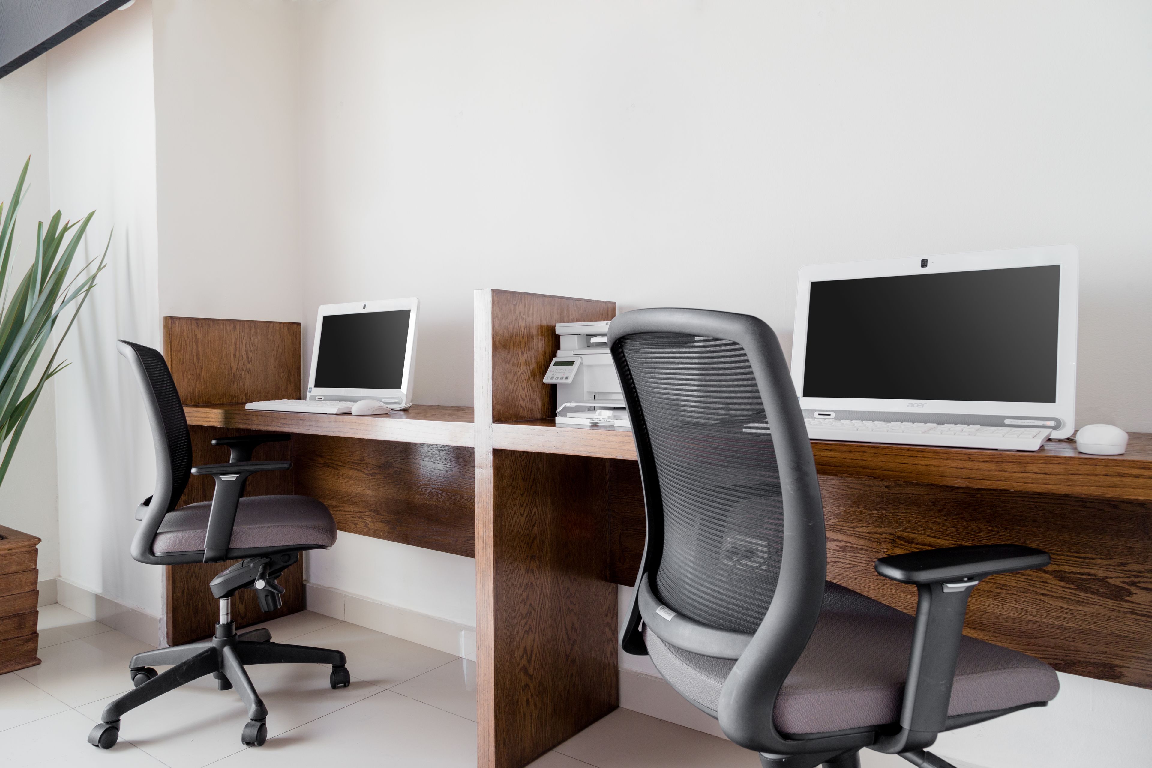 A modern office with two desks, each with a computer and a chair.