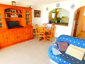 A living room with a blue sofa, wooden dining table, and orange cabinets.