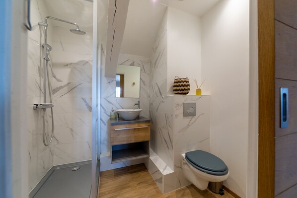 A modern bathroom with a shower, sink, and toilet.