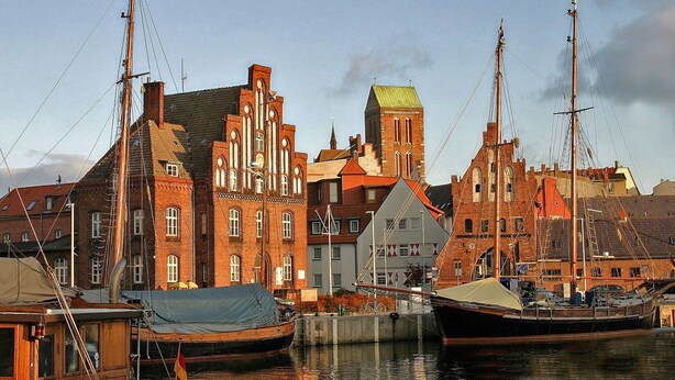 A harbor with traditional brick buildings and a prominent tower. Boats are docked along the water. - Spacious holiday home with a large garden and swimming pond (Stepenitztal)