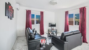A modern living room with black leather sofas, a flat-screen TV, and a small table with two glasses. - Your Dream Holiday Villa with Private Pool in Protaras’s most Exclusive Neighbourhood (Protaras)