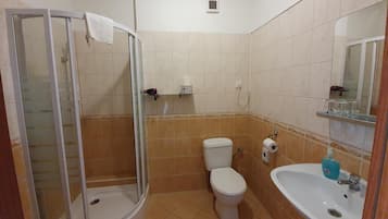 A bathroom with a glass-enclosed shower, a toilet, and a sink with a mirror.