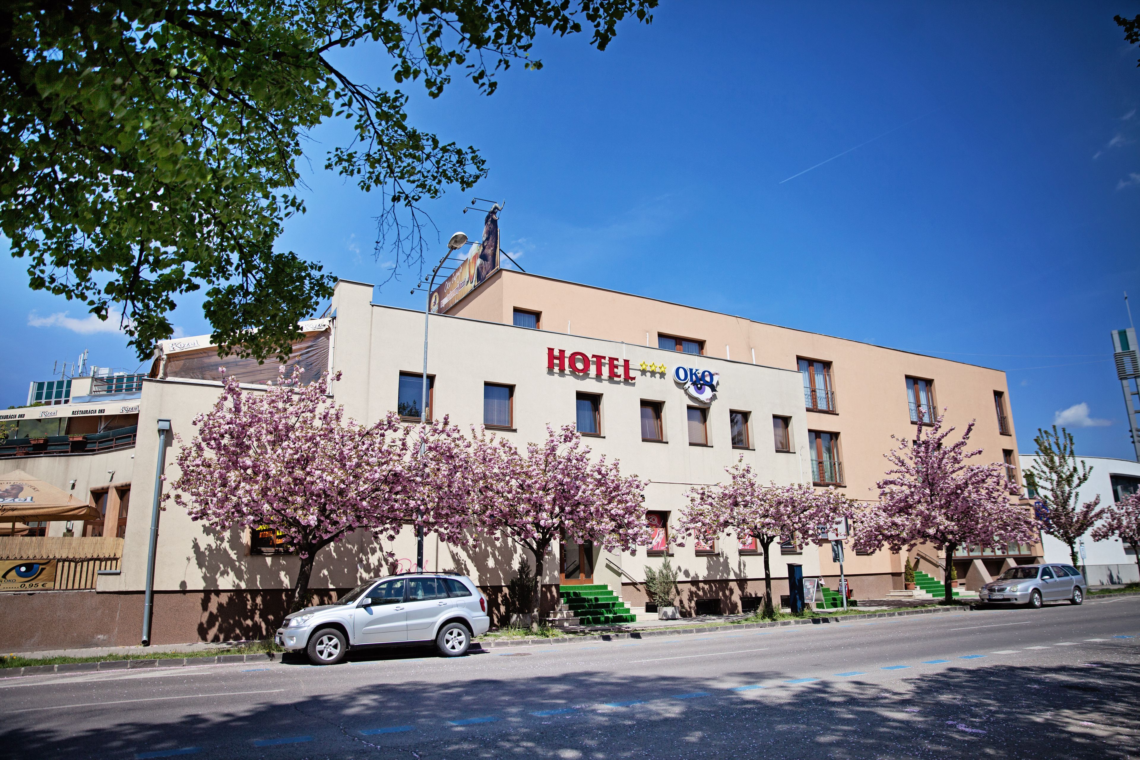 A hotel building with a sign reading "HOTEL OKO" and a car parked in front.