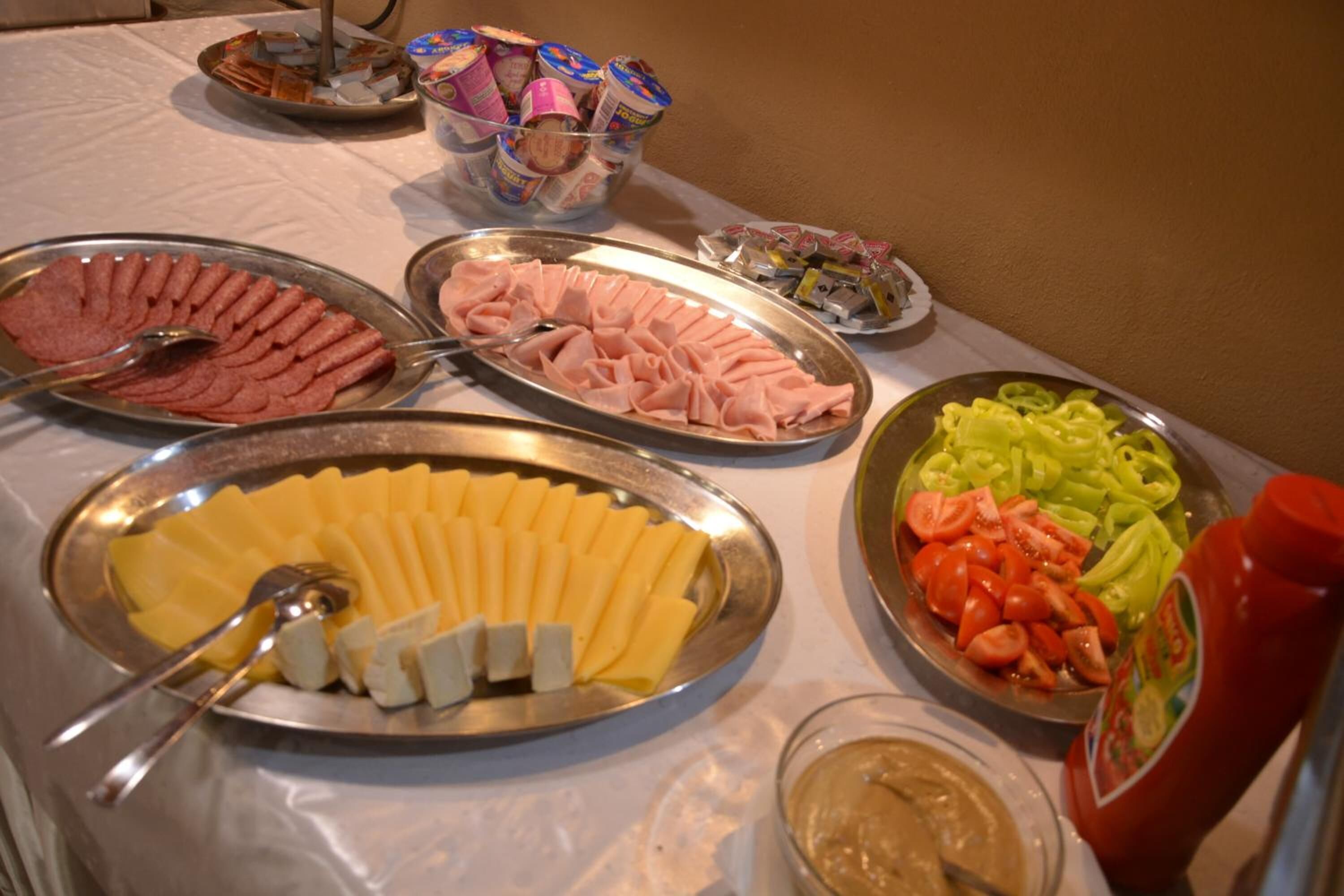 A buffet table with various food items including sliced meats, cheeses, and vegetables.