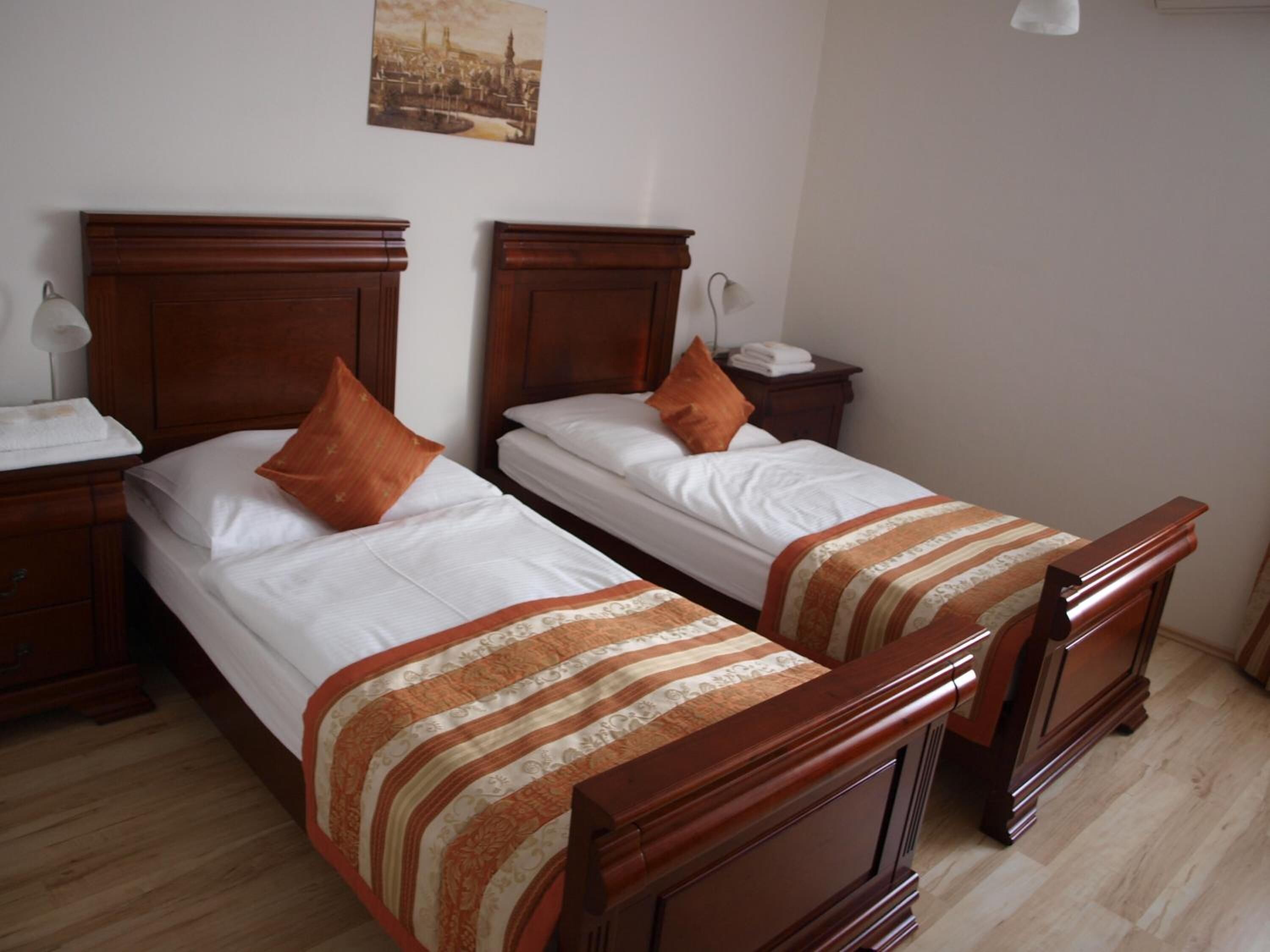 Een hotelkamer met twee houten bedden, witte lakens en streepgoed.