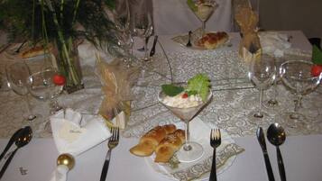 Una mesa de comedor formal dispuesta con varios vasos de vino, tenedores, cucharas y un centro de mesa con una copa de martini y una ensalada.