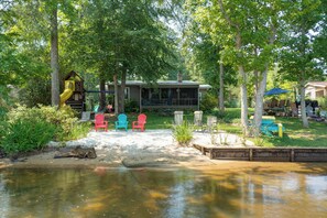 Una propiedad junto al lago con una casa de madera, asientos al aire libre y un parque infantil.