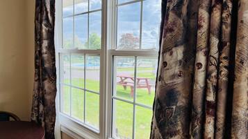 Una habitación con un ventanal, cortinas y vistas a un espacio exterior con mesa de picnic.