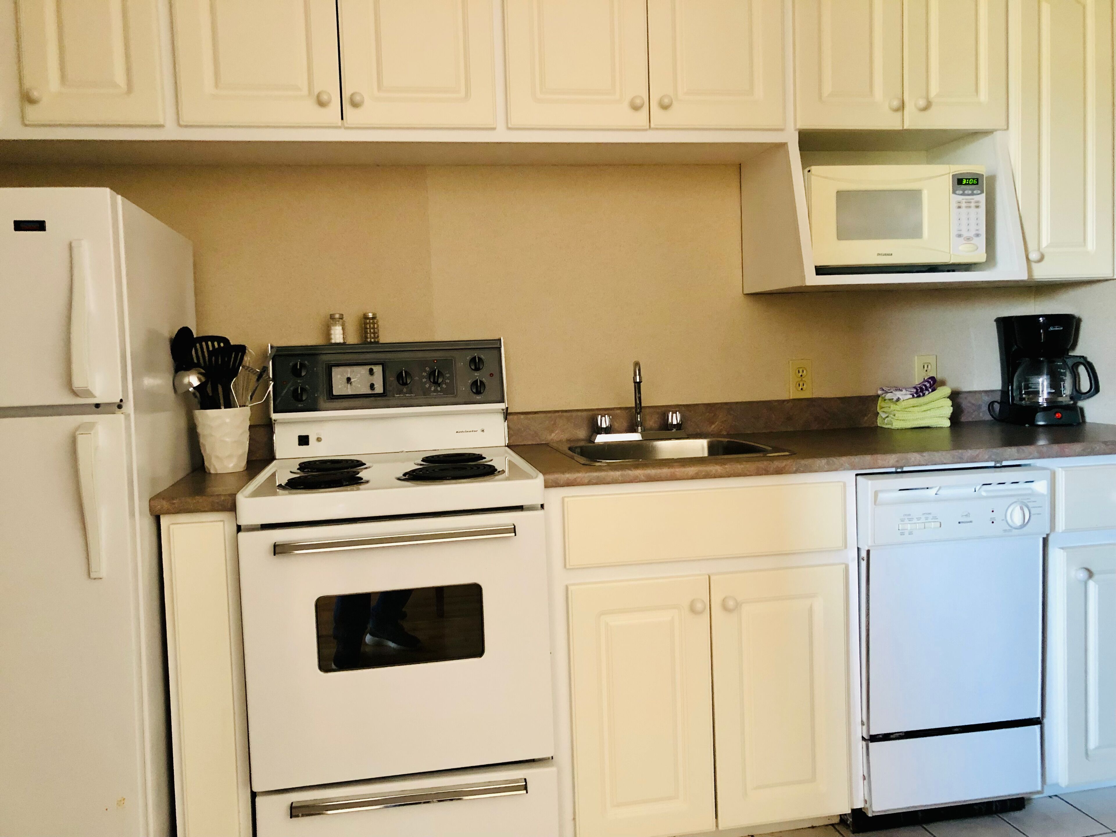 A kitchen with white appliances, including a stove, microwave, refrigerator, and dishwasher.