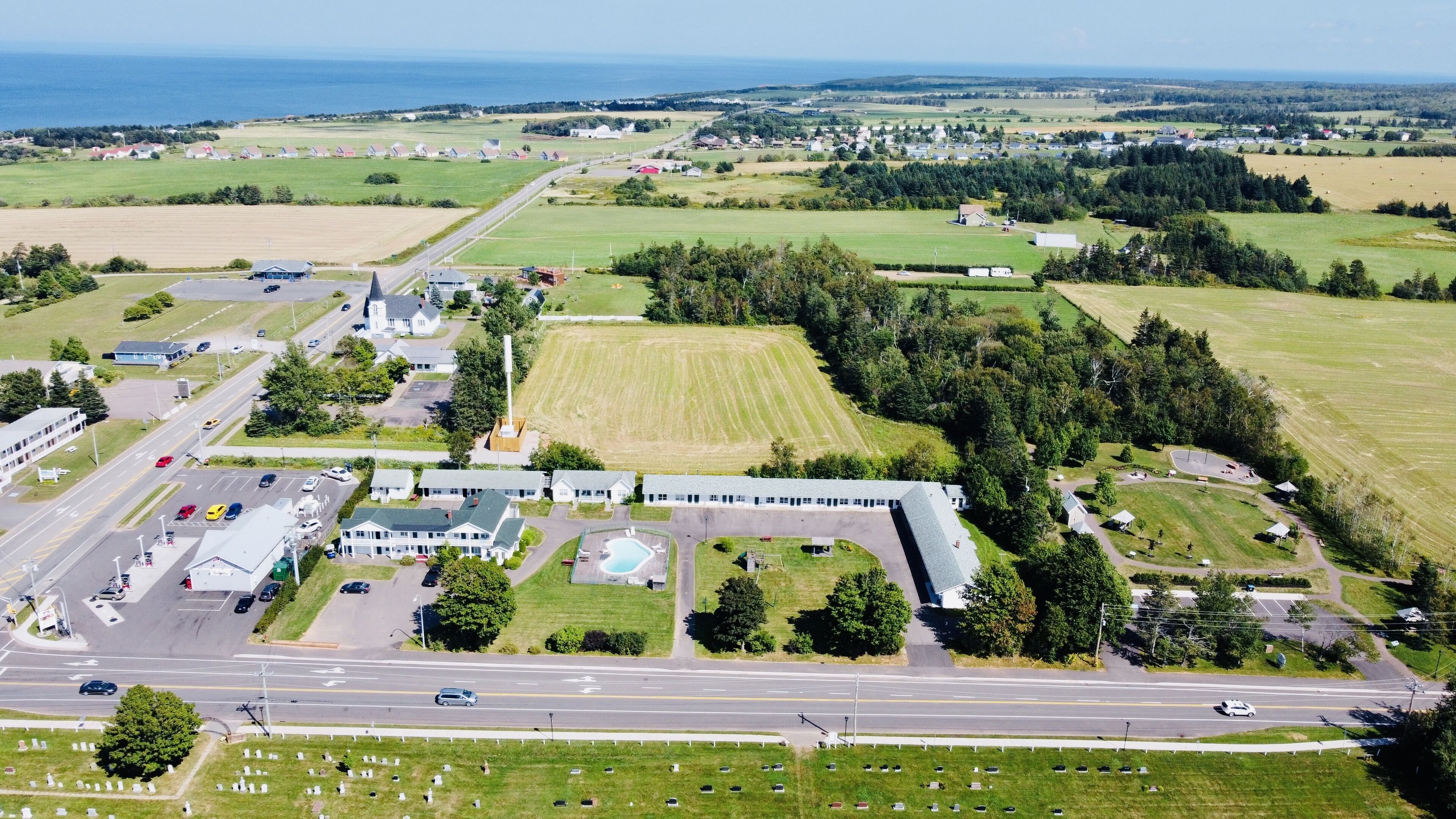 An aerial view of a rural area with a large building complex, roads, and fields.