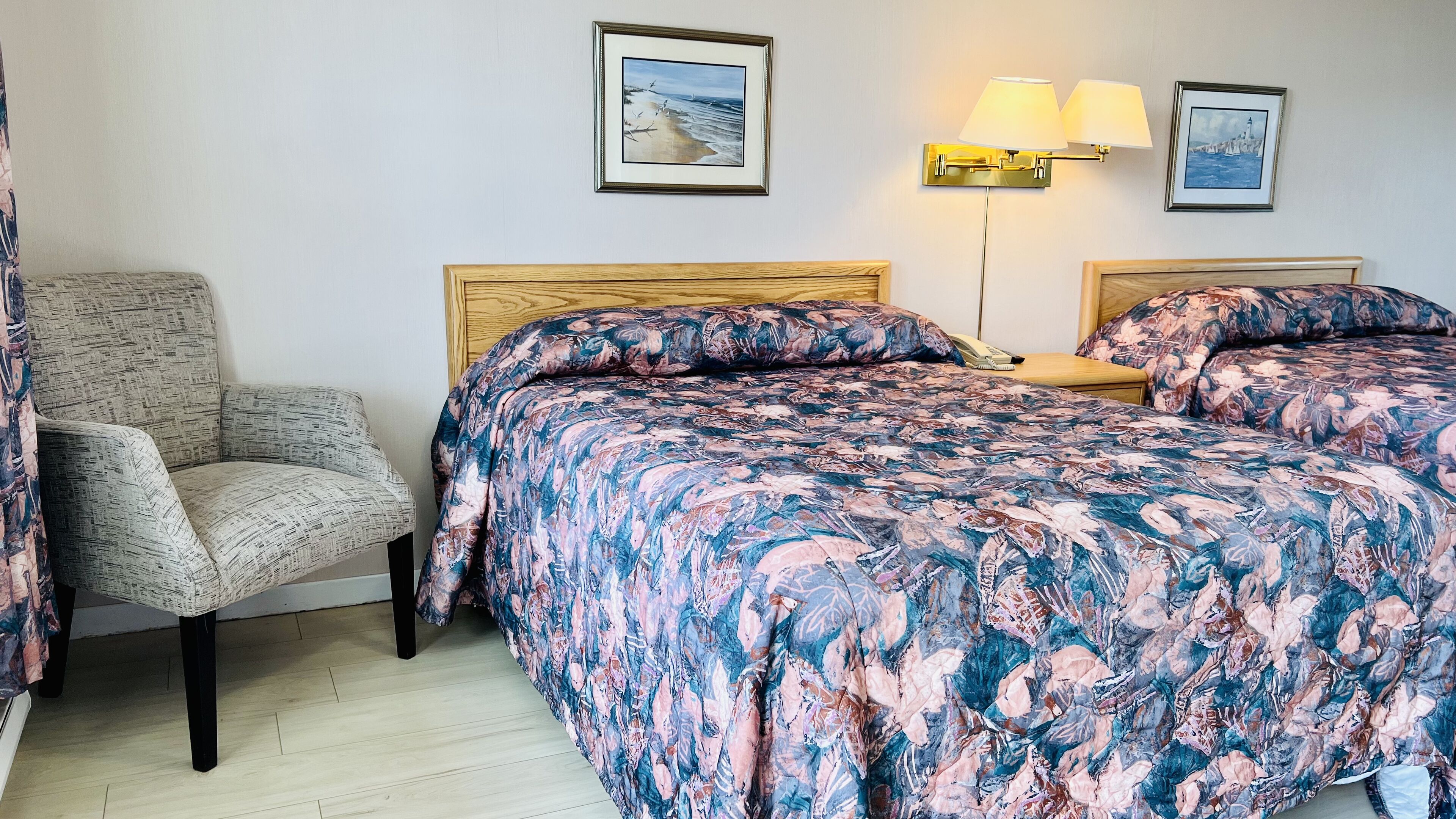 Habitación de hotel con una cama, una silla y dos lámparas fijadas a la pared.