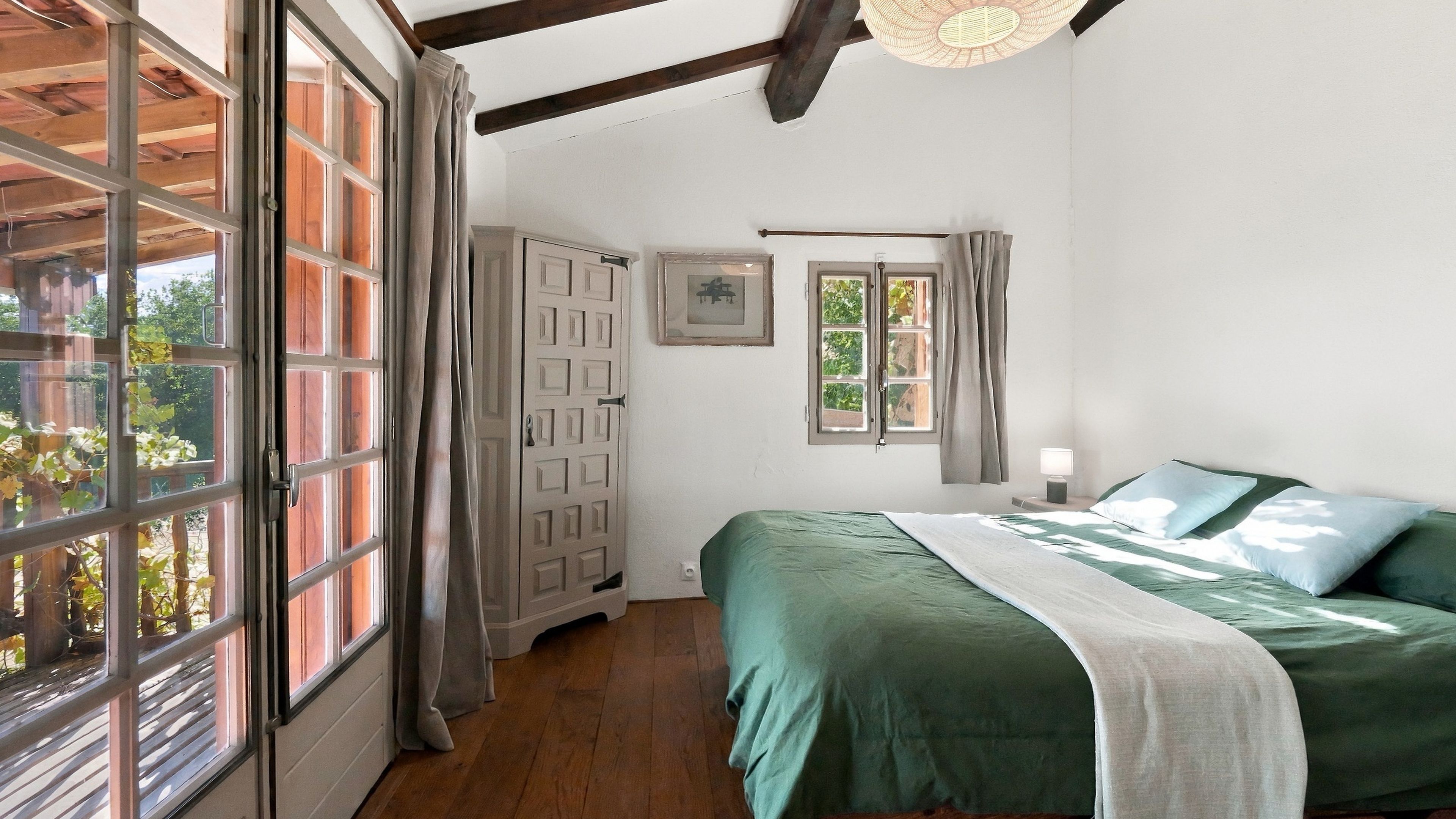 A bedroom with a bed, a wardrobe, and a window with curtains.