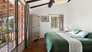 Un dormitorio con cama, armario y ventana con cortinas.