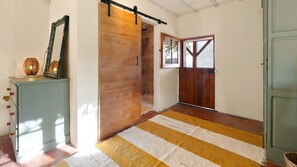 A hallway with a striped rug, a wooden door, and a sliding barn door.