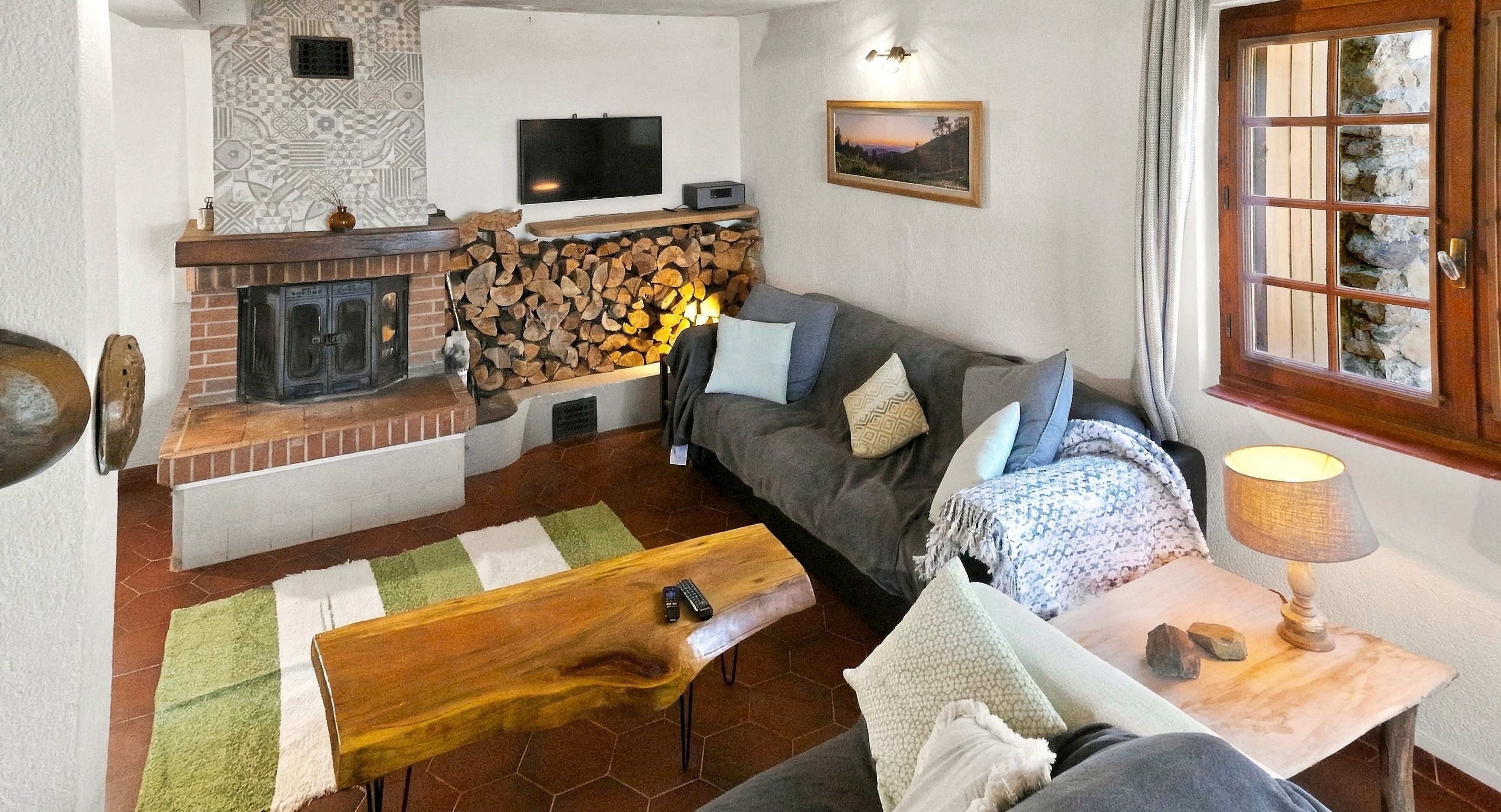 Una sala de estar acogedora con chimenea, un sofá, un televisor y una mesa de centro de madera.