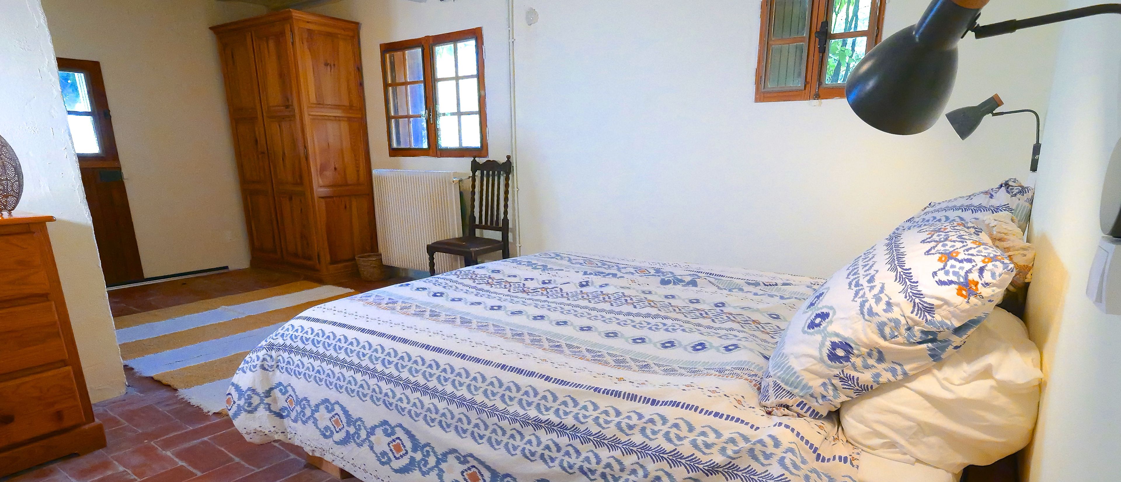 Un dormitorio con una cama, una silla, un armario de madera y un radiador.