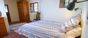 A bedroom with a bed, a chair, a wooden wardrobe, and a radiator.