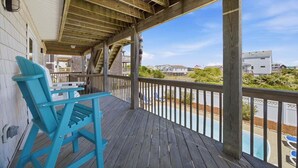 Un espacio al aire libre techado con una terraza de madera, una piscina y vistas a casas vecinas.