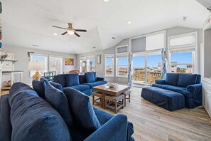 Un salon spacieux, doté d’un grand canapé, d’une table basse en bois et d’un ventilateur de plafond.