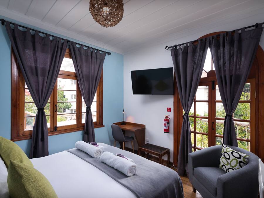 Een hotelkamer met een bed, een bureau, een stoel en een televisie aan de muur.