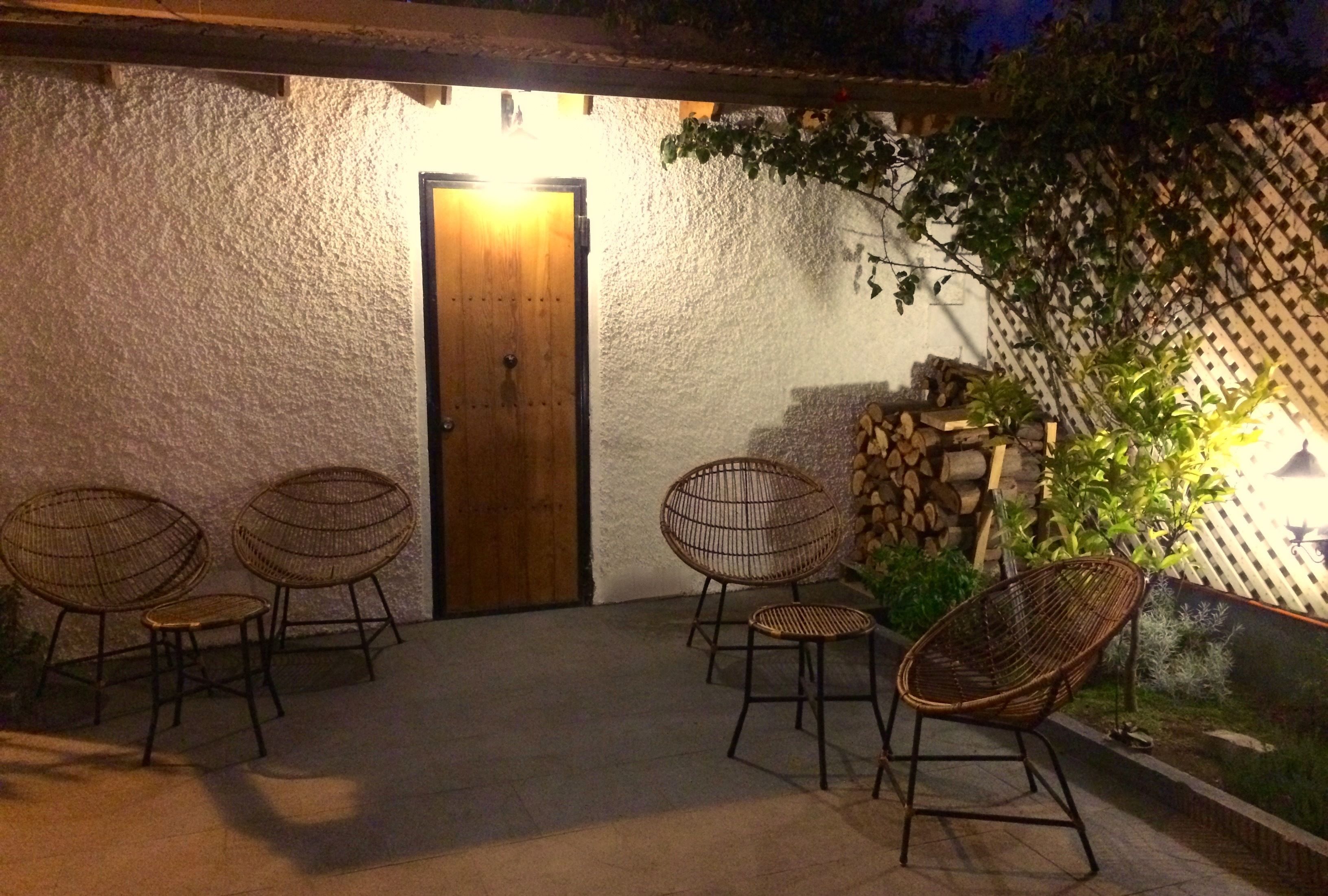 Un espacio al aire libre con sillas de mimbre y una puerta de madera.