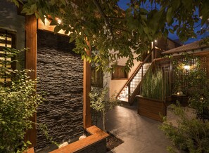 A stone wall with a wooden frame, a staircase, and a garden area with plants and a table. - Esencia Hotel Boutique & Gourmet (Vina del Mar)