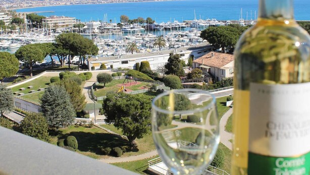 Ein Yachthafen mit Booten, eine Weinflasche und ein Glas auf einem Balkon mit Blick auf die Umgebung.