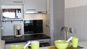 Eine kleine Küche mit Kaffeemaschine, Mikrowelle und Spüle.