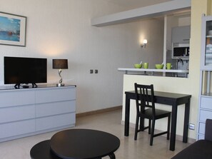 Una cocina moderna con comedor, televisor y un cuadro en la pared.
