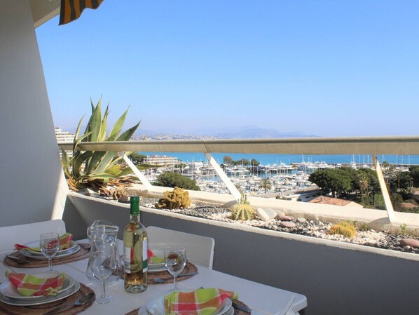 A dining table set for two with a view of a marina and distant mountains.