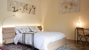 A bedroom with a bed, bedside tables, a lamp, a chair, and artwork on the walls. - Three Rooms (Messina)