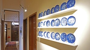 A hallway with a display of blue ceramic plates on shelves. - Three Rooms (Messina)