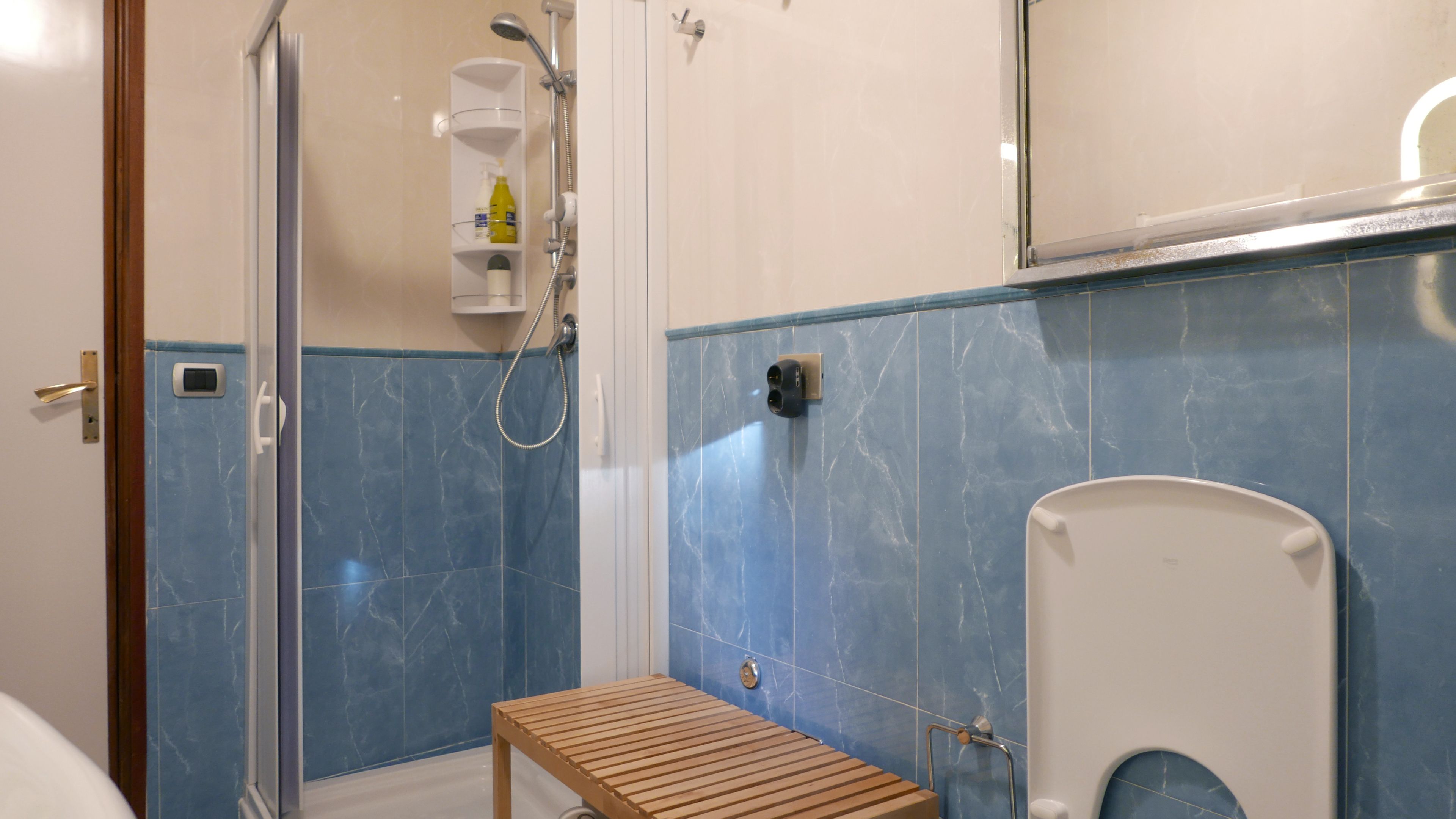 A bathroom with a shower, toilet, and a bench.