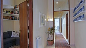 A narrow hallway with a radiator, a potted plant, and a sofa with a cushion. - Three Rooms (Messina)