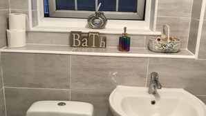 A bathroom with a toilet, sink, and window. - Terraced house available for holiday vacation (London)