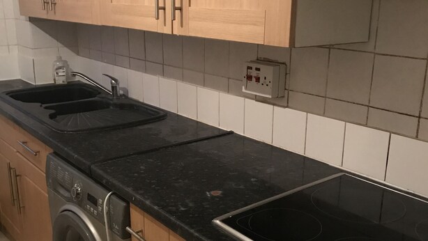 A kitchen with wooden cabinets, a black countertop, a stainless steel oven, and a built-in dishwasher. - Terraced house available for holiday vacation (London)