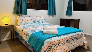 A bedroom with a bed, two windows with curtains, a bedside lamp, and a nightstand. - City House with harbour view! (Dunedin)
