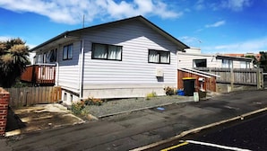 A single-story house with a sloped roof, a front porch, and a fenced yard. - City House with harbour view! (Dunedin)