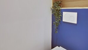 A bathroom with a white toilet, a blue wall, and a wooden shelf above the toilet. - The Alcove Royale, furnished with 3 stars tourism (Versailles)