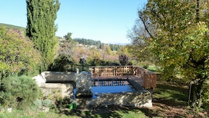 Un jardin agrémenté d’une fontaine, d’une terrasse en bois et offrant une vue sur le paysage environnant.
