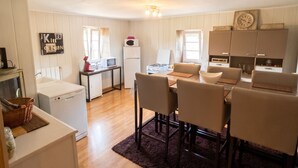 Un espace de vie compact comprenant un coin repas, une kitchenette et un petit coin buanderie.
