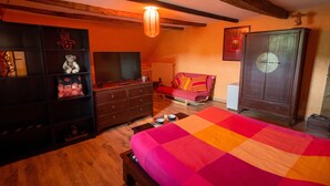 Une chambre à coucher comprenant un lit, une télévision, un canapé, une armoire et un plafond en bois.