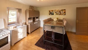 Une cuisine compacte comprenant un coin repas, des meubles de rangement en bois, une cuisinière et une table à manger avec des chaises.