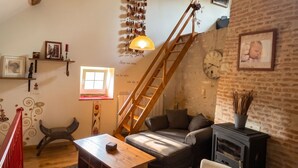 Un salon chaleureux avec un escalier en bois, une cheminée et un coin salon confortable.