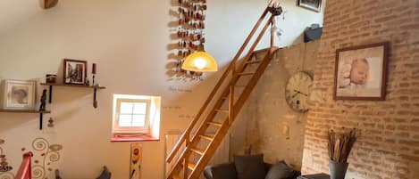 Ein gemütliches Wohnzimmer mit einer Holztreppe, einem Kamin und einer bequemen Sitzecke.