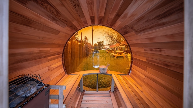 A wooden sauna with a view of a lake and buildings in the distance. - The Islander Inn (Bigfork)