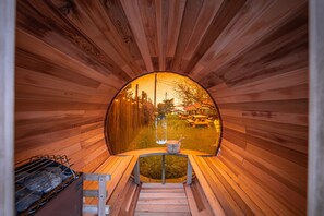 Una sauna in legno con vista su un lago e edifici in lontananza.